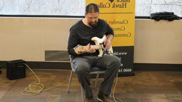 a person sitting in a chair holding a guitar